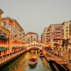 Scenic view of The Pearl Island in Doha, Qatar, featuring a beautiful canal surrounded by luxury apartments and boats under a glowing sunset