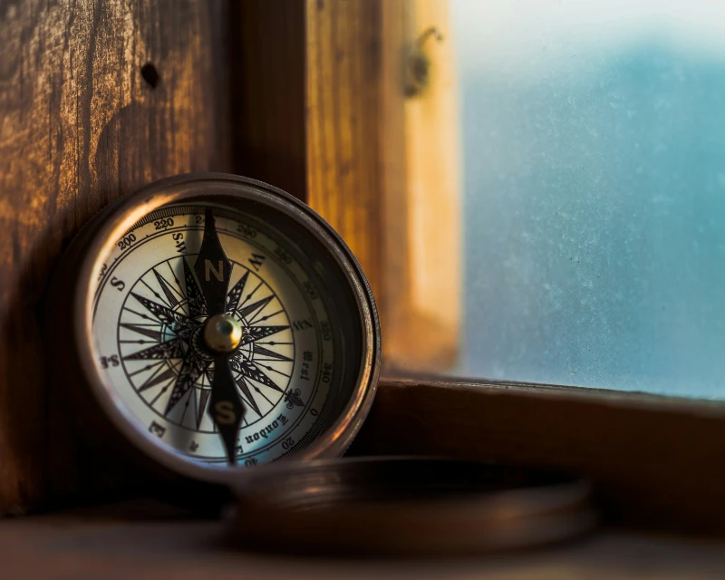 Vintage compass resting on a wooden windowsill, symbolizing travel and exploration - Lery Hago Travels