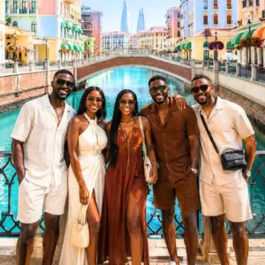 A group of stylishly dressed africans standing on a bridge in the pearl Doha.