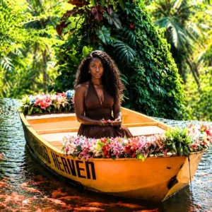 A young African lady sitting in a boat surrounded by Koi fish