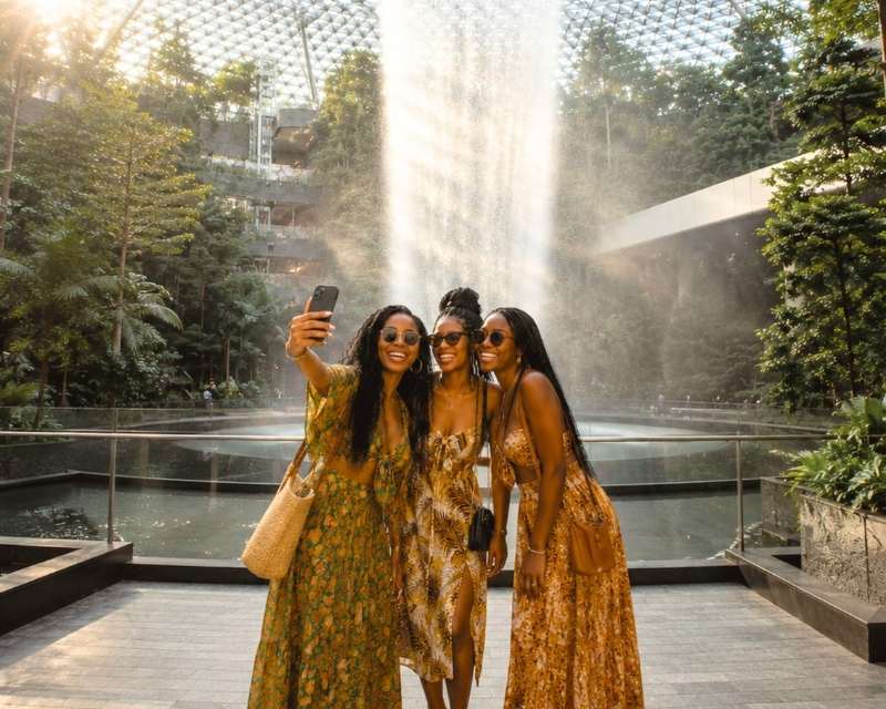 a group of african ladies in their early 20s taking a group selfie in front of the the cloud garden in SIngapore